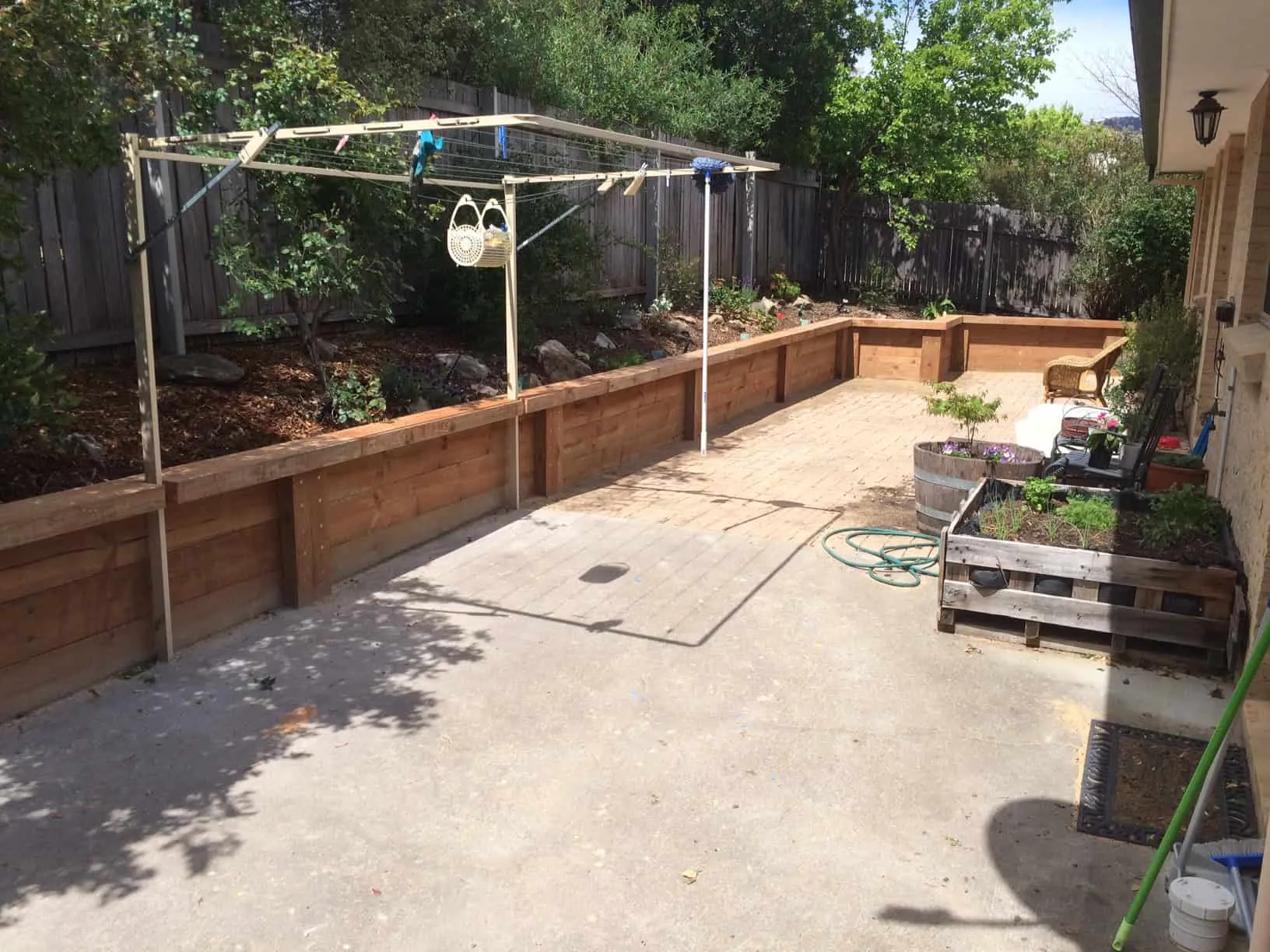 The same yard finished with paving, a restained timber wall and garden beds